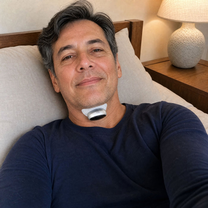 A man reclining against his pillows wearing the VoroHal Sleep Aid under his chin